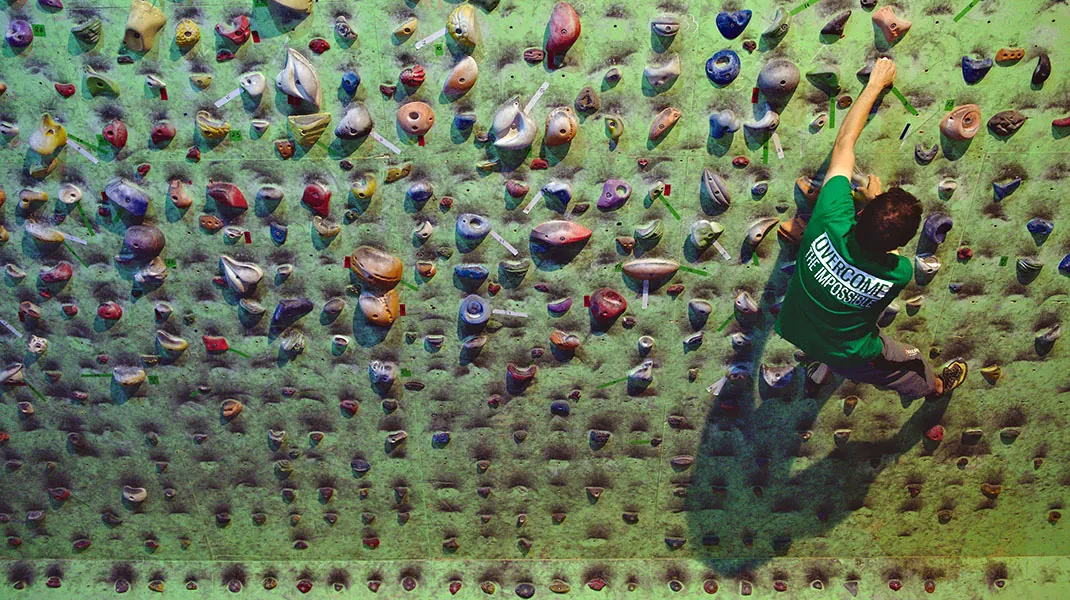 Cățărător pe peretele verde plin de prize colorate